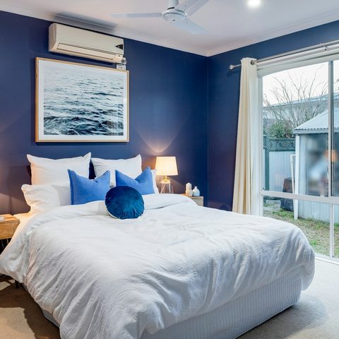 Split AC above the bed in a blue bedroom