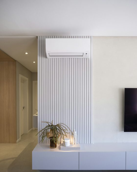 Wall-mounted split AC on a slatted feature wall in a modern living room