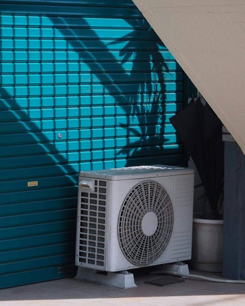 Outdoor AC unit against a teal wall