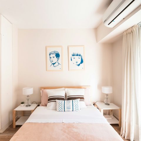 Wall-mounted split AC above a bed in a bright bedroom